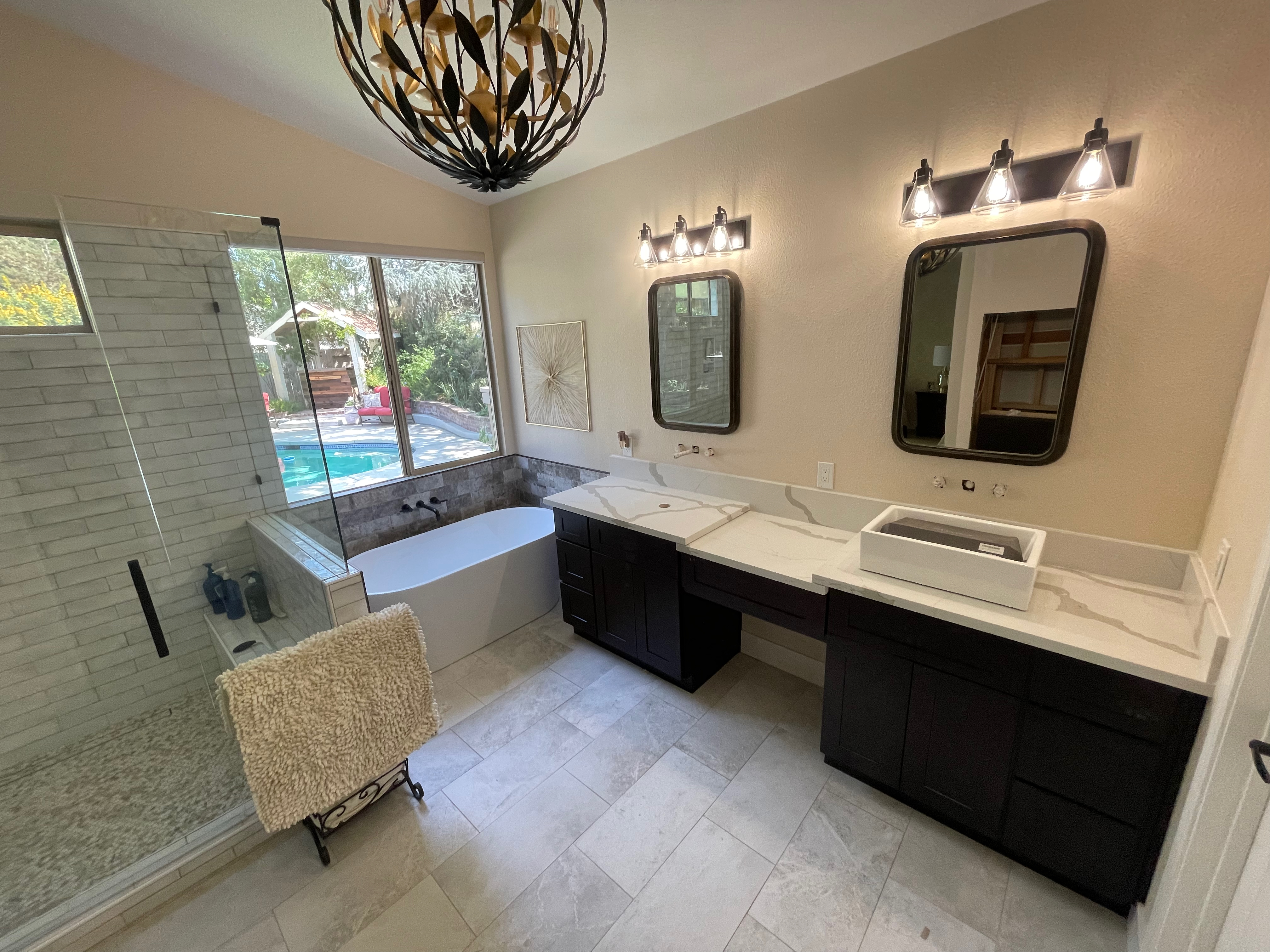 Master bathroom with quartz vanity, freestanding tub, and glass shower